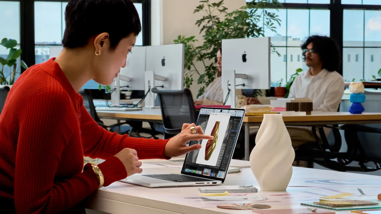 Ofiste masada oturan bir kullanıcı PROLED XDR ekranlı MacBook Pro'nun ekranına dokunuyor